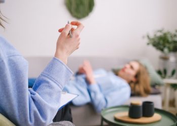 A person lying on a sofa and talking to a therapist.