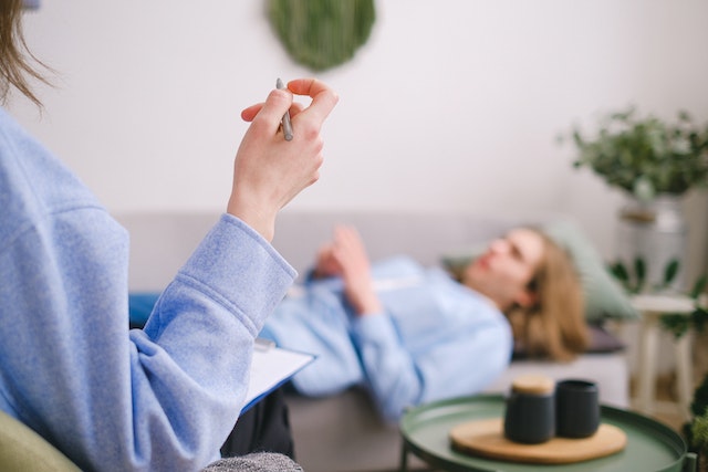 A person lying on a sofa and talking to a therapist.